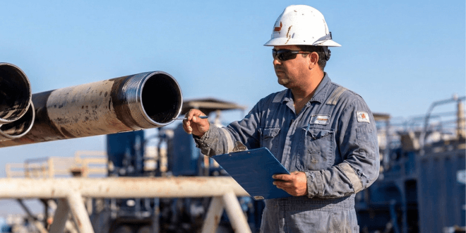 Oilfield technician supervising drill pipe on a rig floor, inspecting tubular connections during drilling operations to ensure proper handling, torque verification, and compliance with manufacturer specifications.