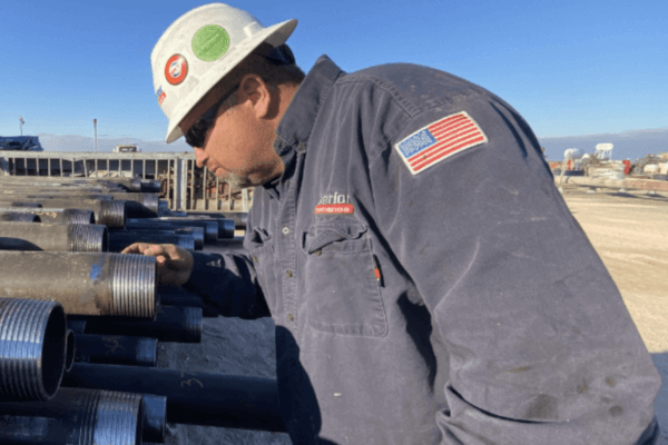 A field service supervisor employed by Superior Performance, wearing a white hard hat, a blue FRS shirt with an american flag on it, while inspecting pipe  (1)