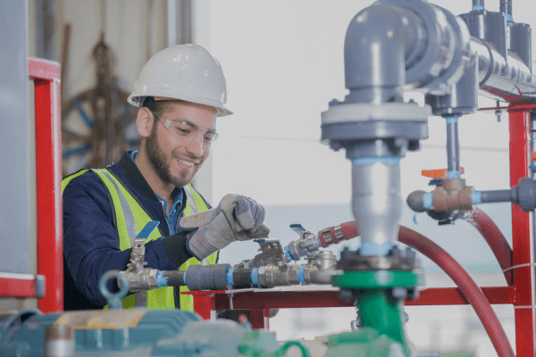 An oilfield worker wearing a hard hat, blue fire retardant shirt, and yellow vest using tools to to fix power equipment at Superior Performance shop headquarters (1)