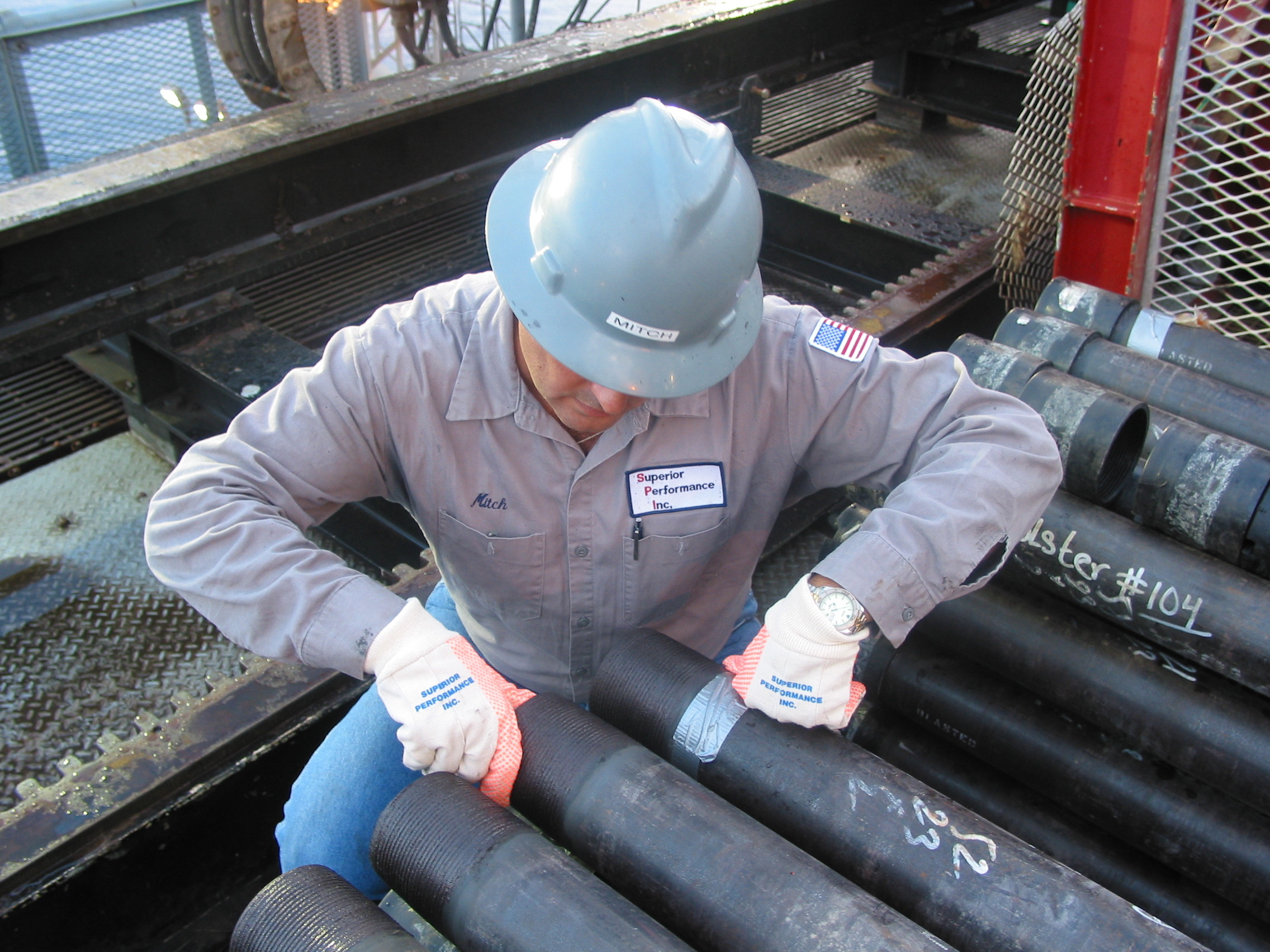 A Superior Performance field service supervisor in the field wearing a hard hat and FRC clothing doing work on a pipe