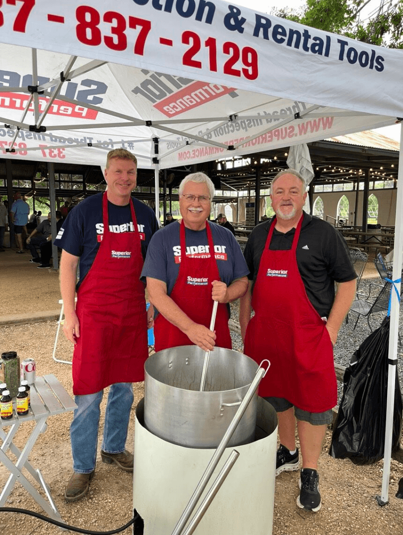 Superior Performance team members volunteering at a community event while wearing branded aprons under a company tent.